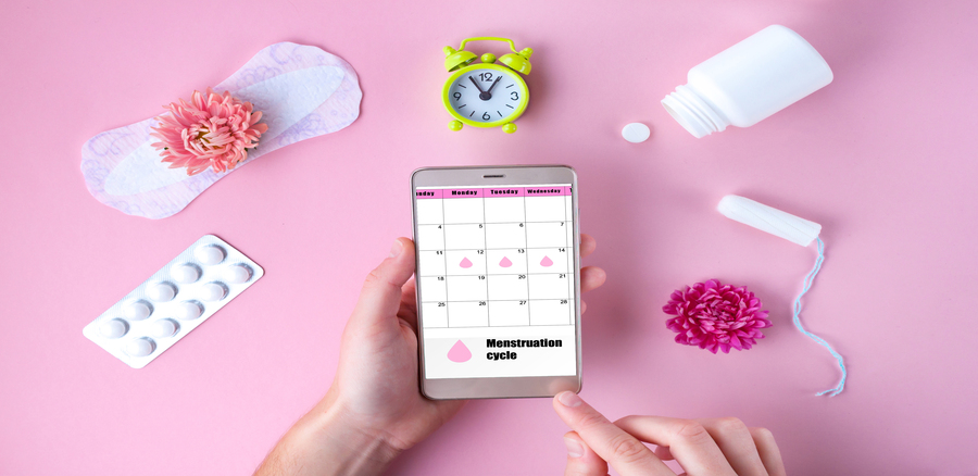 Tampon, feminine, sanitary pads for critical days, feminine calendar, alarm clock, pain pills during menstruation and a pink flower on a pink background. Care of hygiene during menstruation. Tracking the menstrual cycle and ovulation.