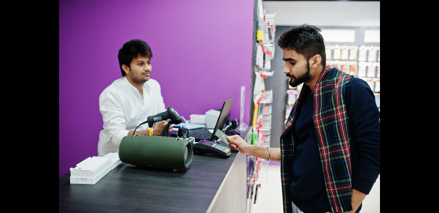 Indian man customer buyer pay for his new smartphone for seller by credit card at mobile phone store South asian people and technologies concept Cellphone shop
